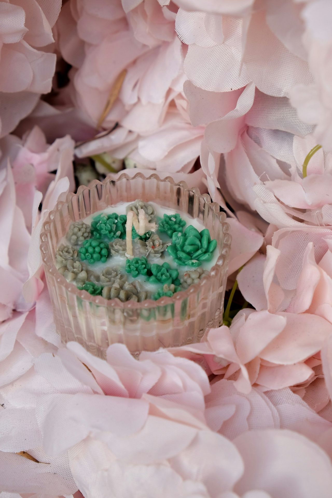 a cupcake sitting on top of a table surrounded by pink flowers
